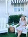 Young girl sitting in the garden ona white children's Adirondack chair