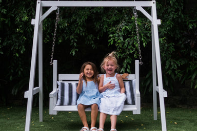Girls sit on My Little Manor White timber Swing Bench seat.