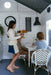 Children play cafe inside My Little Manor cubby house cafe. Boys sit on kids bistro chairs around a white round dining table as young girl serves them.