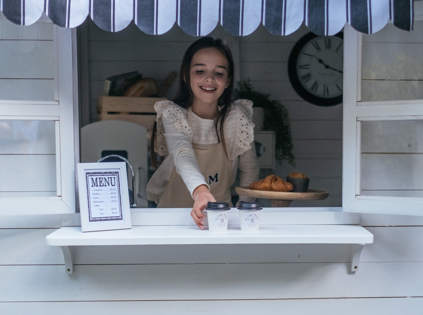 Young girl plays cafe in her white timber cubby house