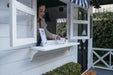 Young girl plays cafe in her white timber cubby house