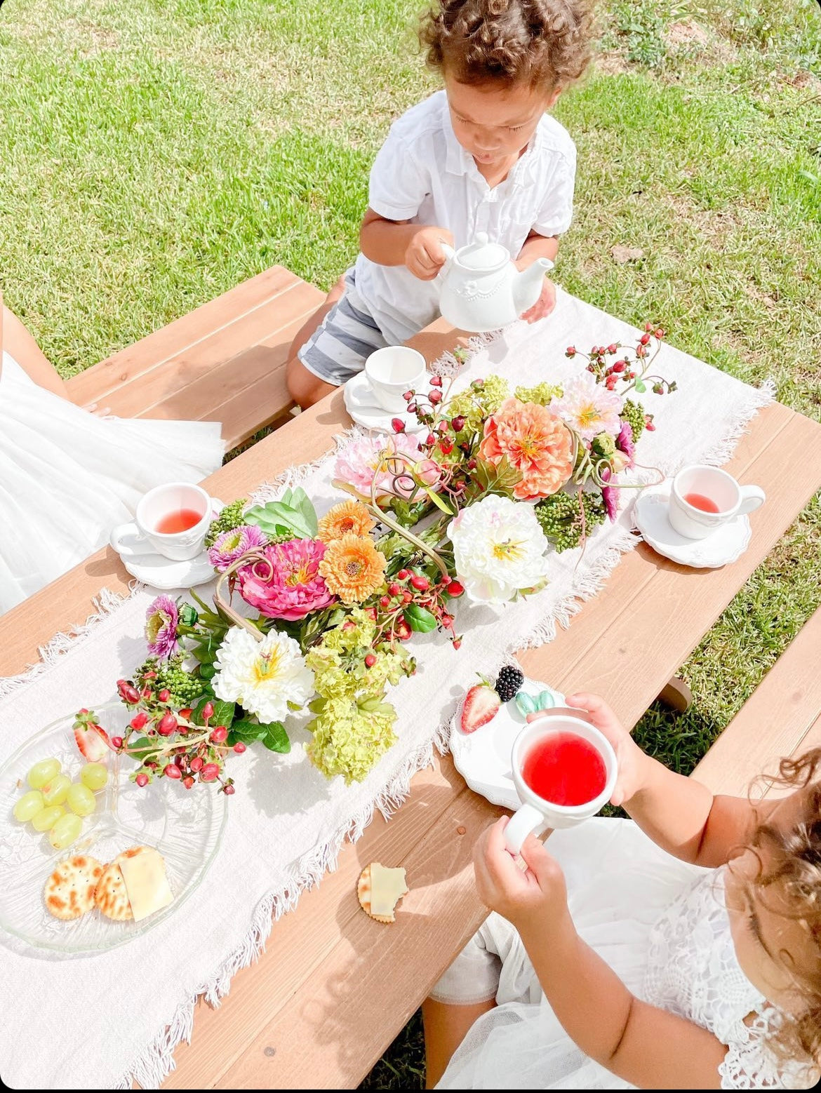 Young children have a tea party in the garden on a My Little Manor Outdoor Table Setting