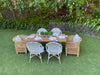 Kids grey and white bistro chairs sit around a rectangular timber outdoor. Two kids Malawi chairs sit at the head of the table. 