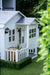 Large timber white cubby house with grey roof.