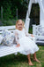 Young girl sits on white timber outdoor kids swing bench seat