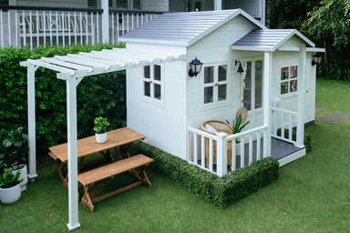 White timber pergola attached to white cubby house with grey roof. 